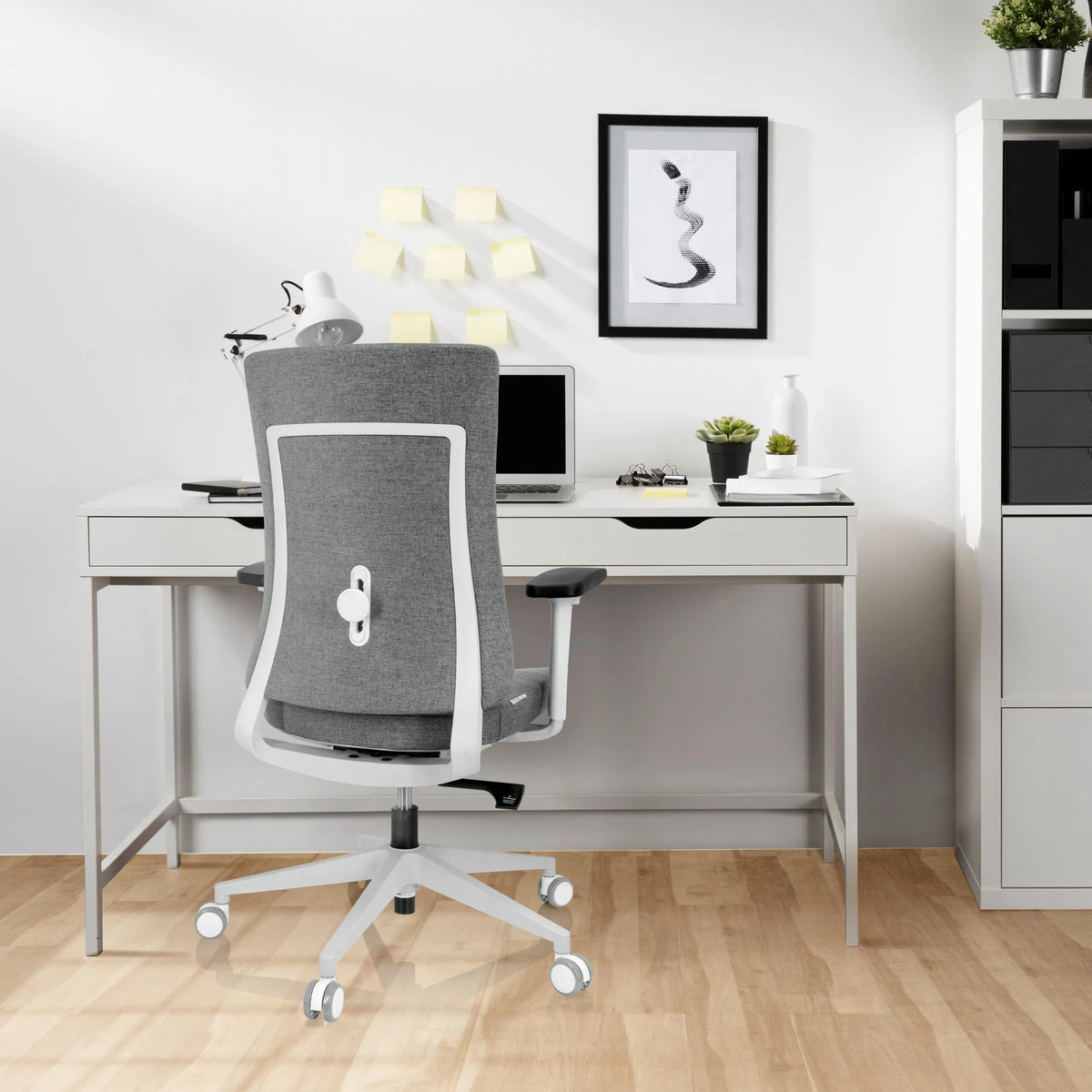Sedia da ufficio professionale COMFIO WP grigia con struttura e rotelle bianche davanti a una scrivania di hjh OFFICE