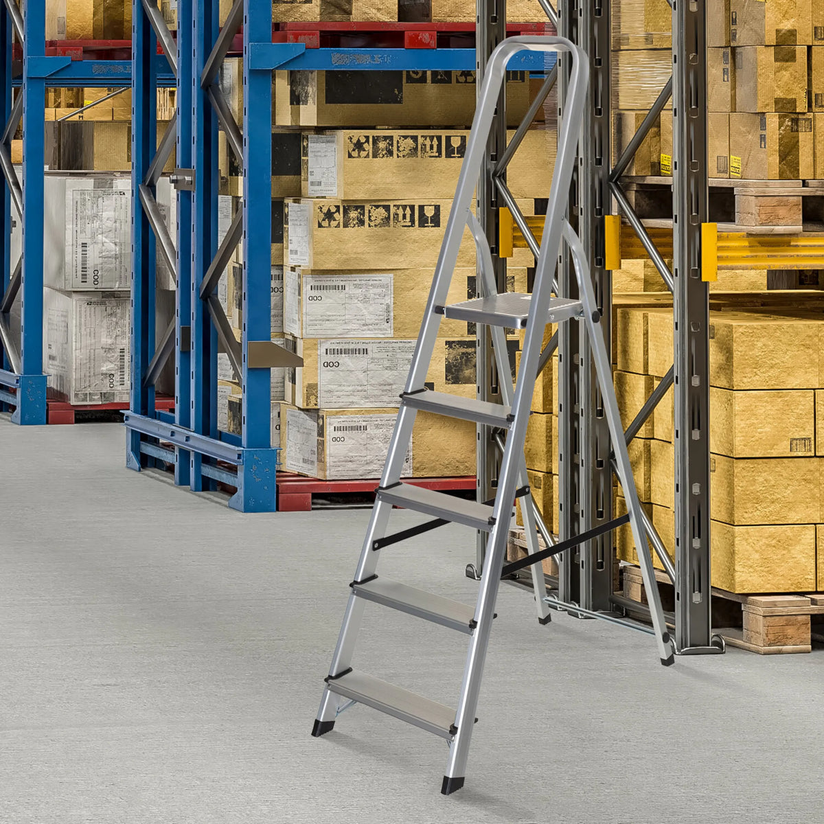 Scala richiudibile in alluminio a cinque pioli SOLID III in un magazzino davanti a uno scaffale di hjh OFFICE