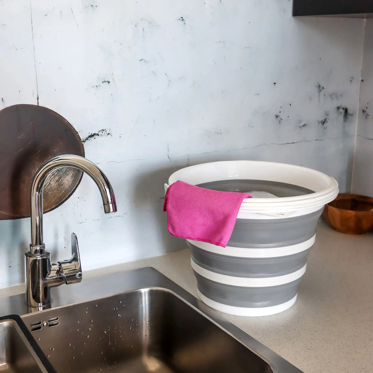 Contenitore pieghevole CLEAN SILR grigio e bianco con un panno rosa su una superficie di lavoro accanto a un lavandino di hjh OFFICE