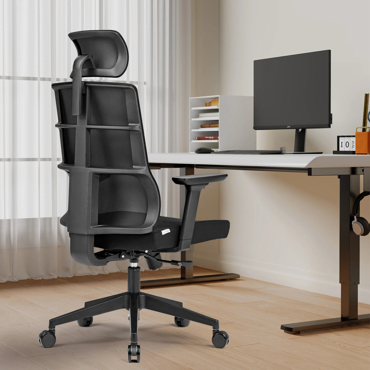 Sedia da ufficio professionale SPINIO PRO nera con poggiatesta e braccioli davanti a una scrivania di hjh OFFICE