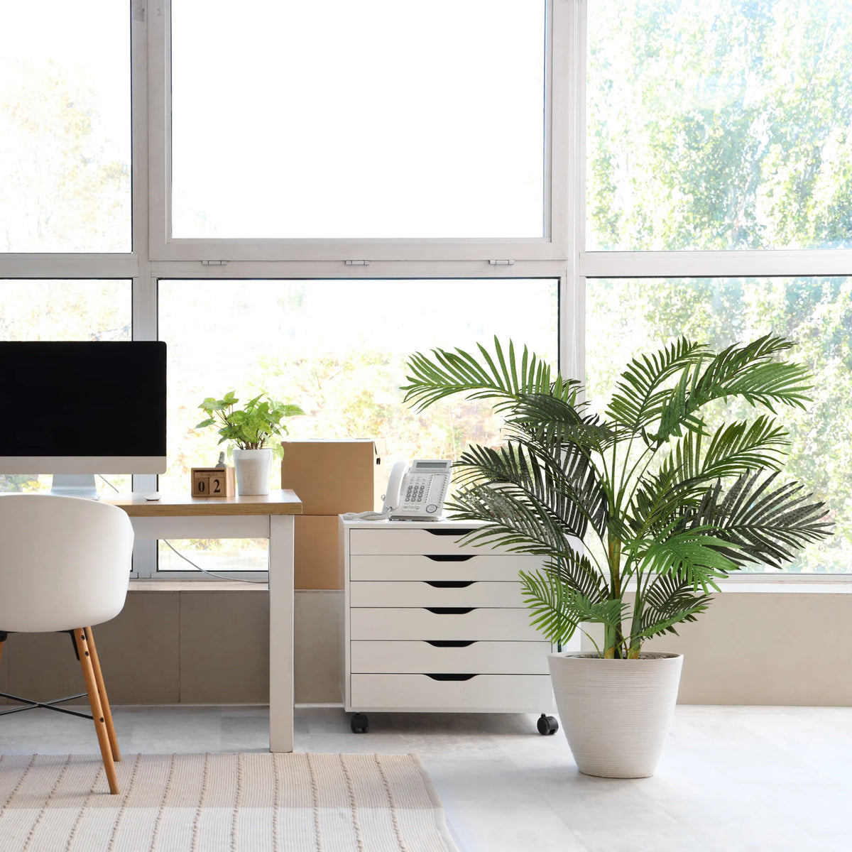 Pianta artificiale verde ARECA II in un vaso bianco accanto a un cassettiera bianca con ruote di hjh OFFICE