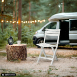 Sedia da esterno TRAVANO bianca in un ambiente boschivo accanto a un camper di hjh LIVING (immagine generata dall’IA)