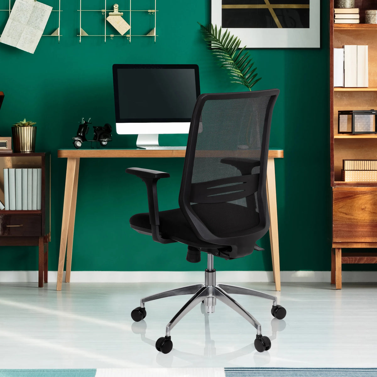 Sedia da ufficio professionale PROFONDO nera con schienale in rete e base cromata davanti a una scrivania di hjh OFFICE