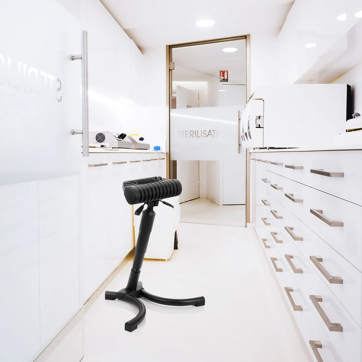 Ausilio per la posizione eretta TOP WORK 33 nero con seduta imbottita e base a stella in un ambiente di sterilizzazione luminoso di hjh OFFICE