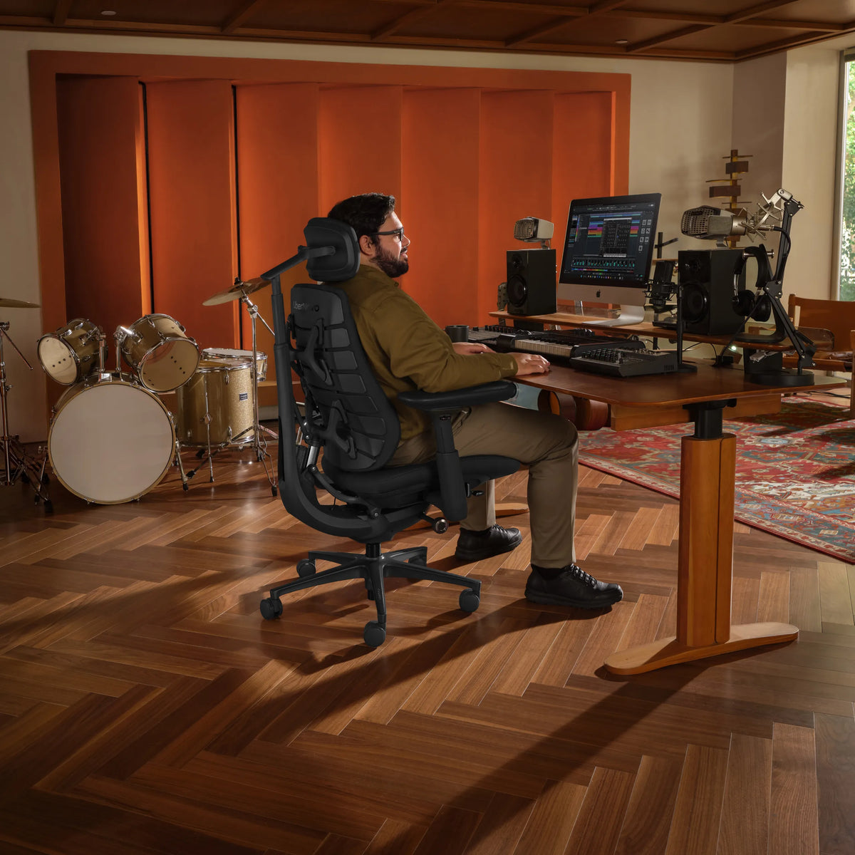 Sedia da ufficio LiberNovo Maxis Elektric in grafite in uno studio musicale con scrivania e batteria di Libernovo