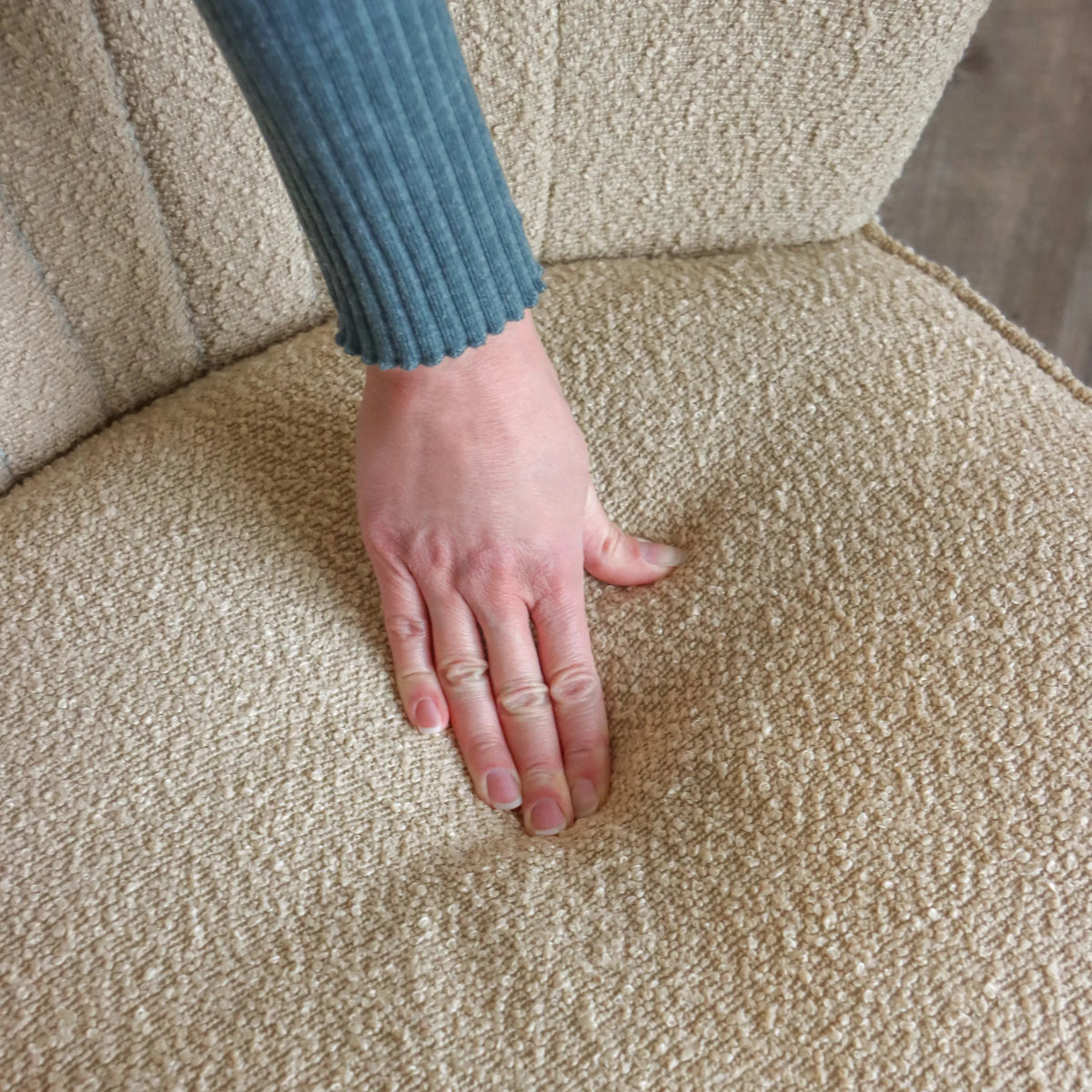Tessuto strutturato beige della poltrona lounge MANISO con una mano appoggiata sulla seduta di hjh LIVING