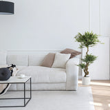 Pianta artificiale verde ACACIA in un vaso bianco accanto a un divano di hjh OFFICE