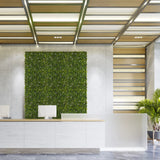 Pannello vegetale verde MORE GREEN I come verde verticale su una parete in cemento chiaro in un'area reception di hjh OFFICE