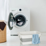 Contenitore pieghevole CLEAN SILW grigio e bianco accanto a una lavatrice di hjh OFFICE