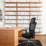High-end Sedia da ufficio NOVA PRO I nera con poggiatesta e schienale in rete davanti a una scrivania in legno di hjh OFFICE