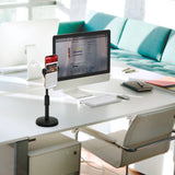 Supporto per cellulare e tablet FLEXMOBI II nero su una scrivania bianca accanto a un monitor di hjh OFFICE
