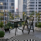 Tavolo pieghevole TRAVANO T1 nero di 79 × 79 cm su un balcone di hjh LIVING (immagine generata dall’IA)