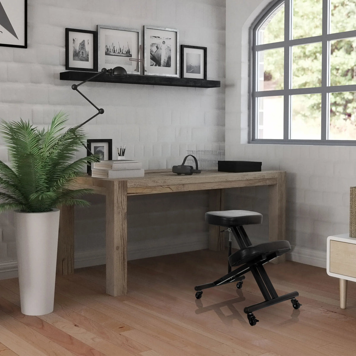 Sgabello per ginocchia ORTHONI nero con ruote davanti a una scrivania in legno in una stanza luminosa di hjh OFFICE