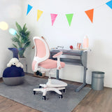Sedia per bambini rosa KID ERGO con braccioli bianchi e rotelle a una scrivania di hjh OFFICE