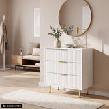 Cassettiera bianca Hjelle K con frontali scanalati e maniglie e gambe color oro di hjh LIVING (immagine generata dall’IA)