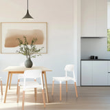 Sedia a quattro gambe SCANDI E in bianco con gambe in legno chiaro in una zona pranzo di hjh LIVING
